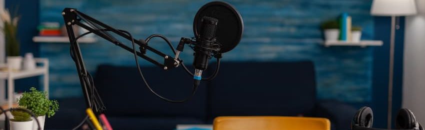 Empty home recording studio with podcast equipment. Professional microphone and headphones used for online broadcast on social media. Electronic audio livestream technology on desk.