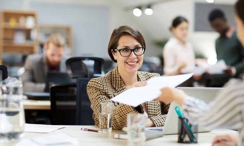 smiling-businesswoman-giving-documents-to-YLNUKBJ.jpg